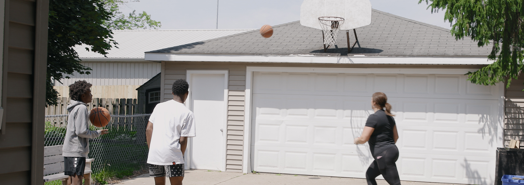 Foster mom plays basketball in the driveway with two foster youth boys